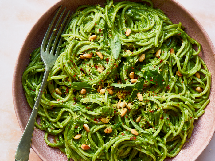 A bowl of spaghetti with green sauce of roasted nuts.