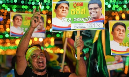 A man cheers while holding a banner of Sajith Premadasa against a background of green lights