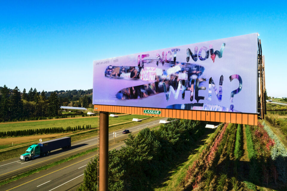 a light purple billboard depicting a clouded reflection with wiped away sections revealing a photograph of protestors and text reading, "if not now, when?"