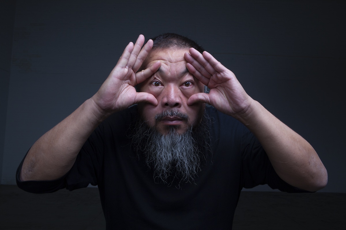 A portrait of an Asian man with a long beard spreading open the folds around his eyes.