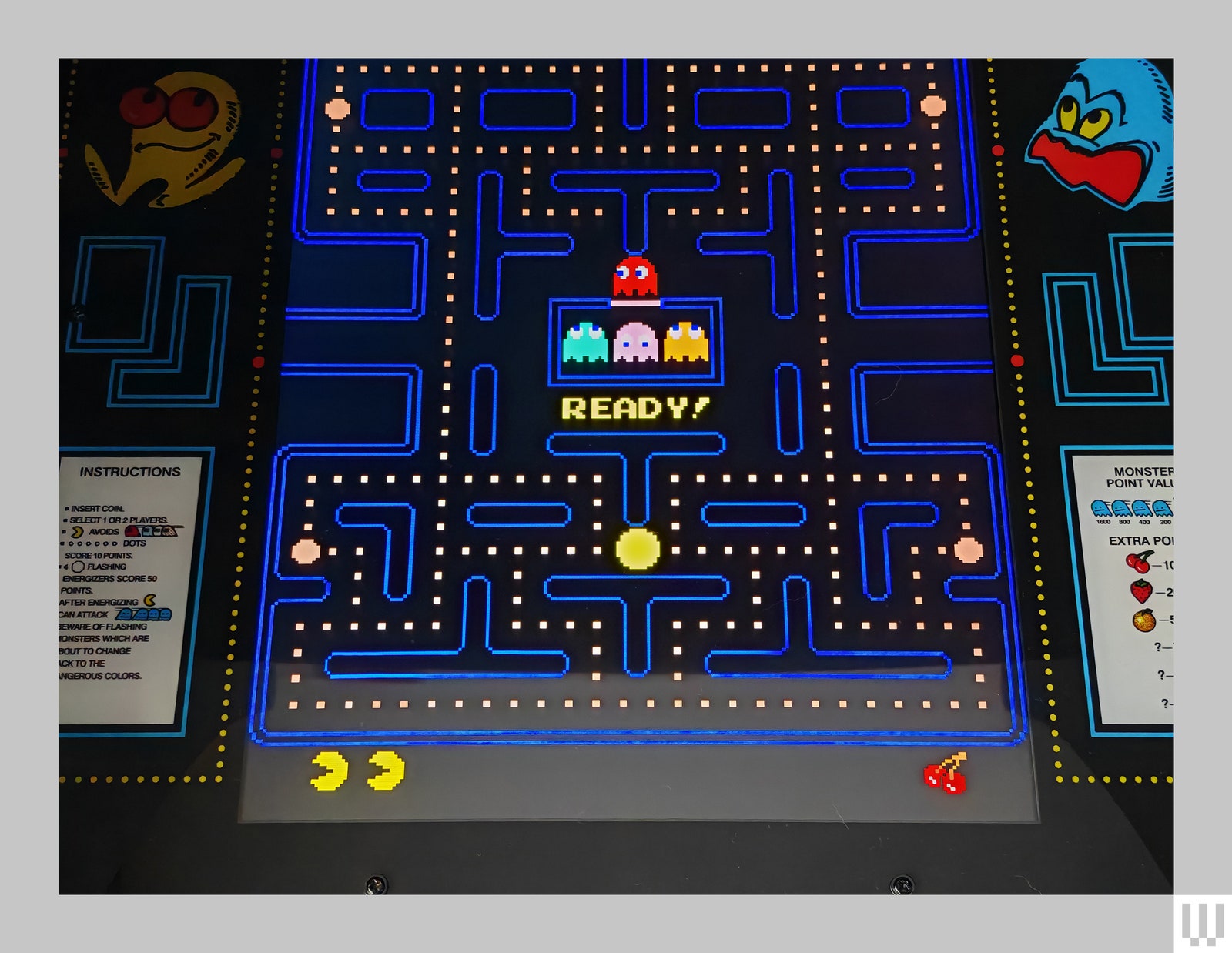 Closeup of arcade machine screen showing a maze with yellow dots within the path lines