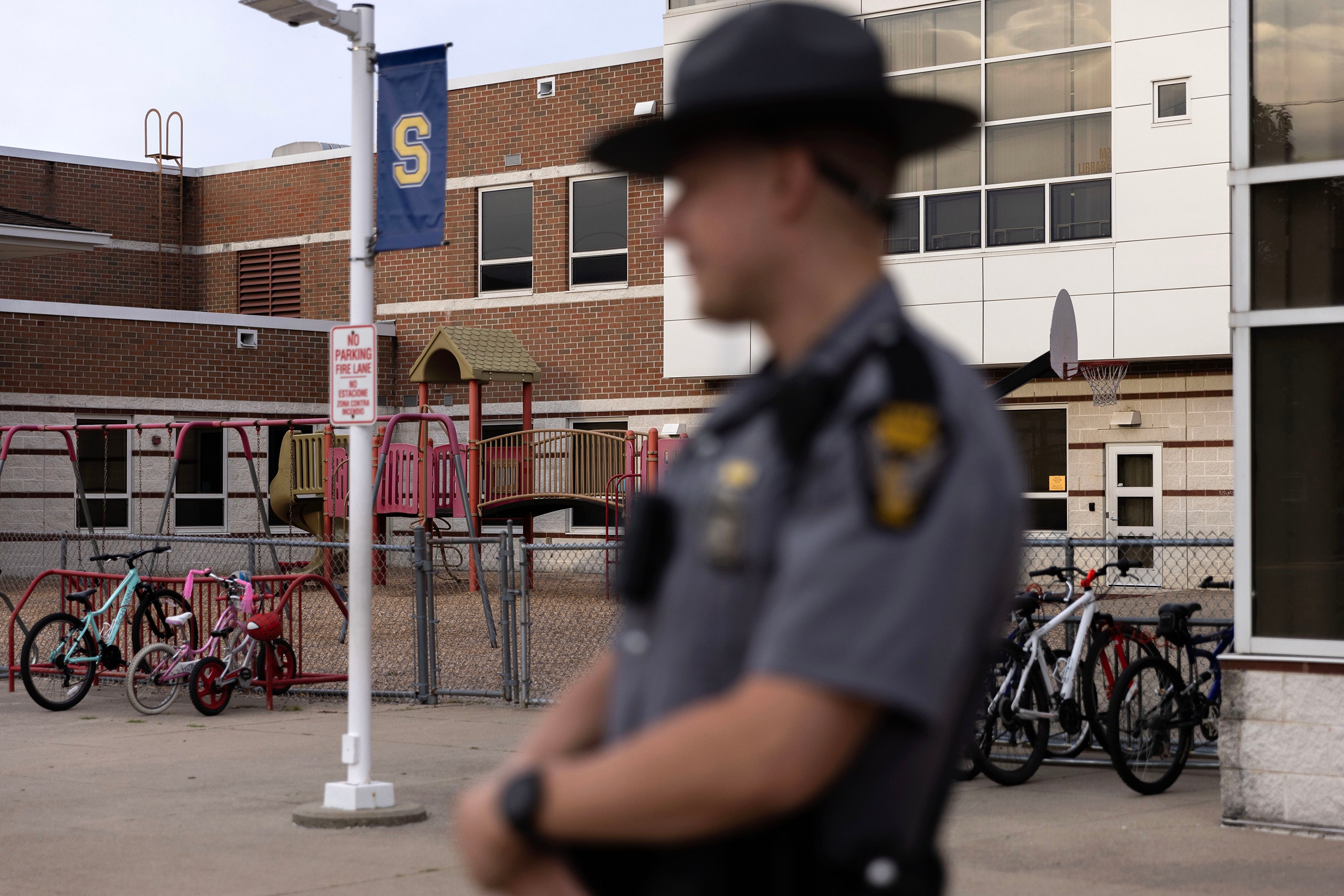 A uniformed officer standing in front of a school.