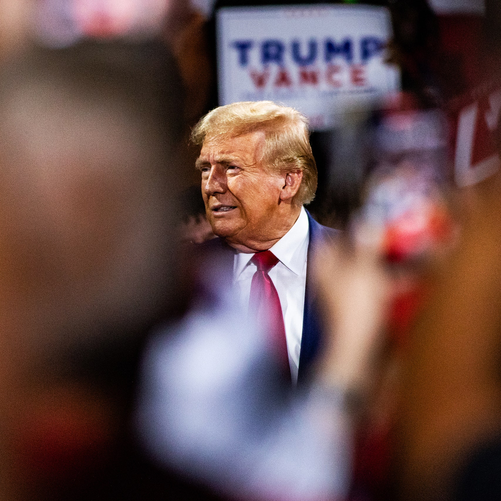 Former U.S. President Donald Trump walking through a crowd in Flint Michigan. Trump is seen through the arms of attendees.