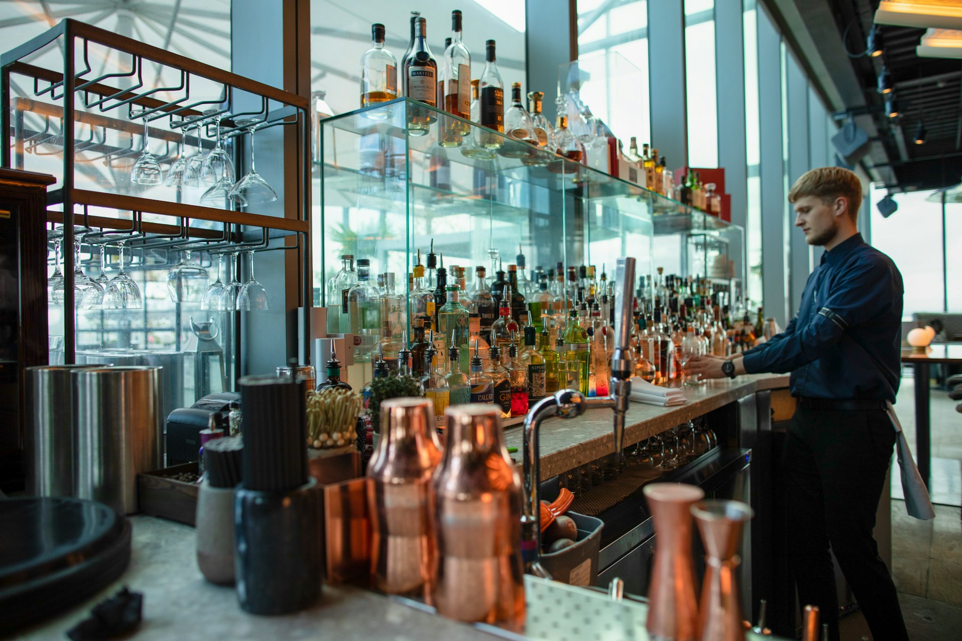 A bartender in front of a range of bottles and mixing tools at the rooftop bar and restaurant 20 Stories, Manchester