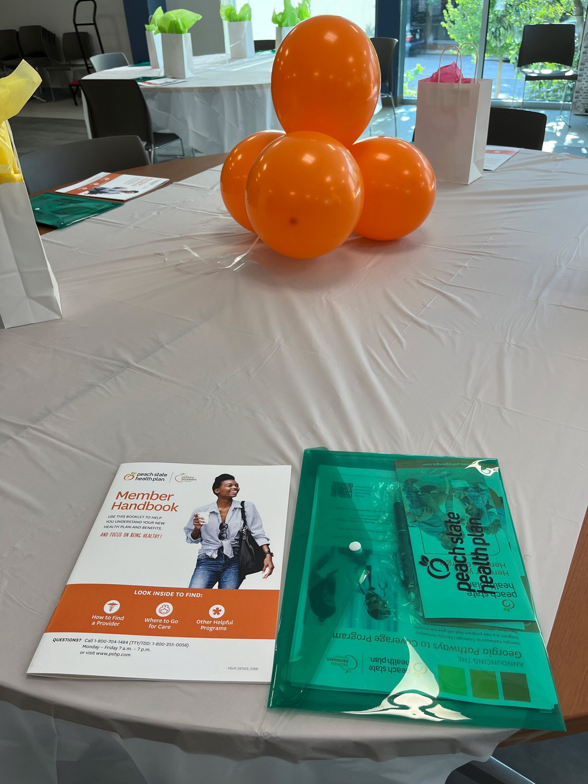 A photo of a table with orange balloons and pamplets.