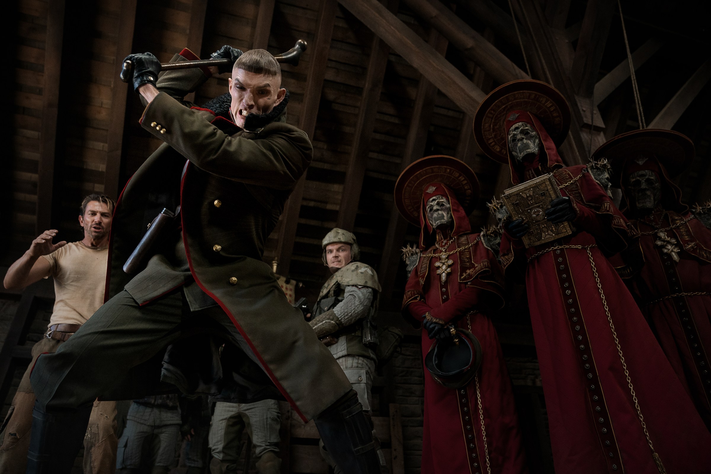 Admiral Noble (Ed Skrein) mid-bash, with his priests behind him