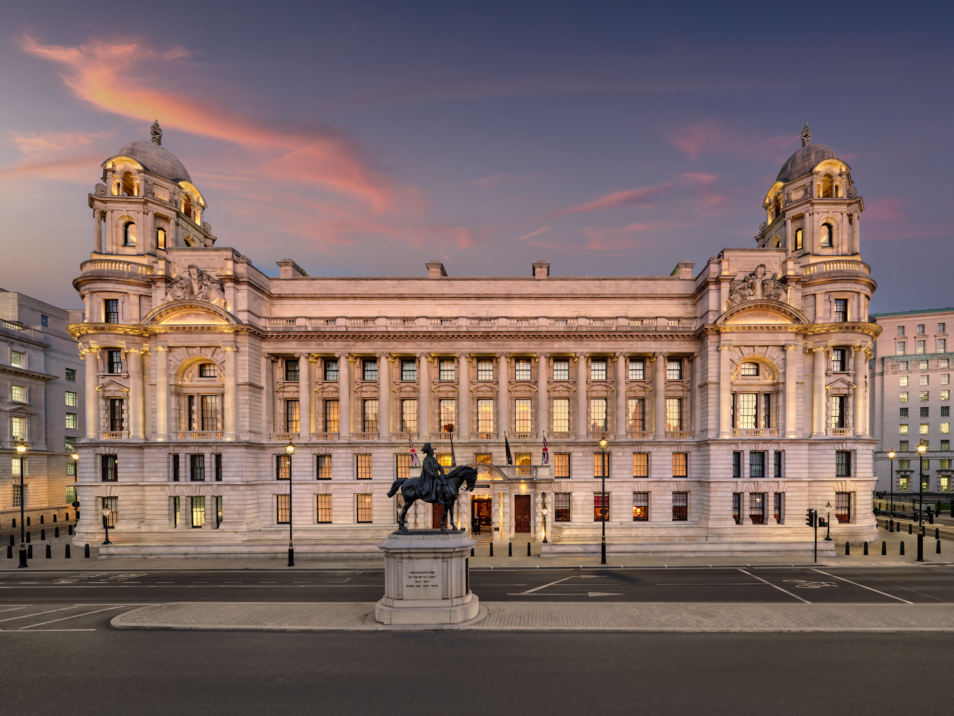 The exterior of a grand hotel building with domed turrets at either end at sunset