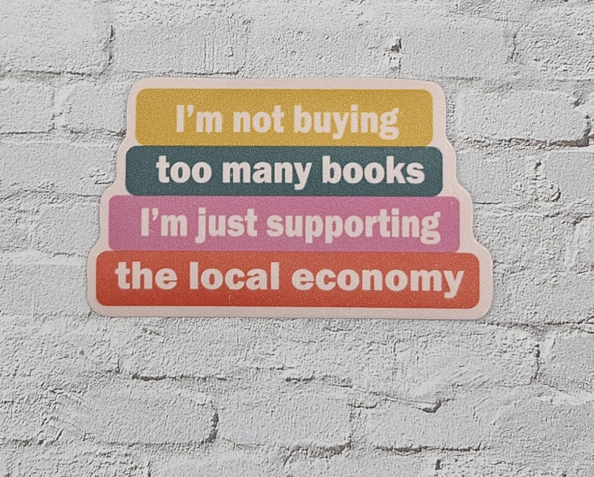 Image of a vinyl sticker designed to look like a stack of books that says "I'm not buying too many books, I'm just supporting the local economy"