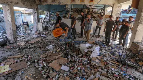 EPA People gather around a burnt out school, with what look like cans of food all over the floor, while searching for survivors after an Israeli strike at the al-Jaouni school in Nuseirat refugee camp, in central Gaza, on 11 September 2024