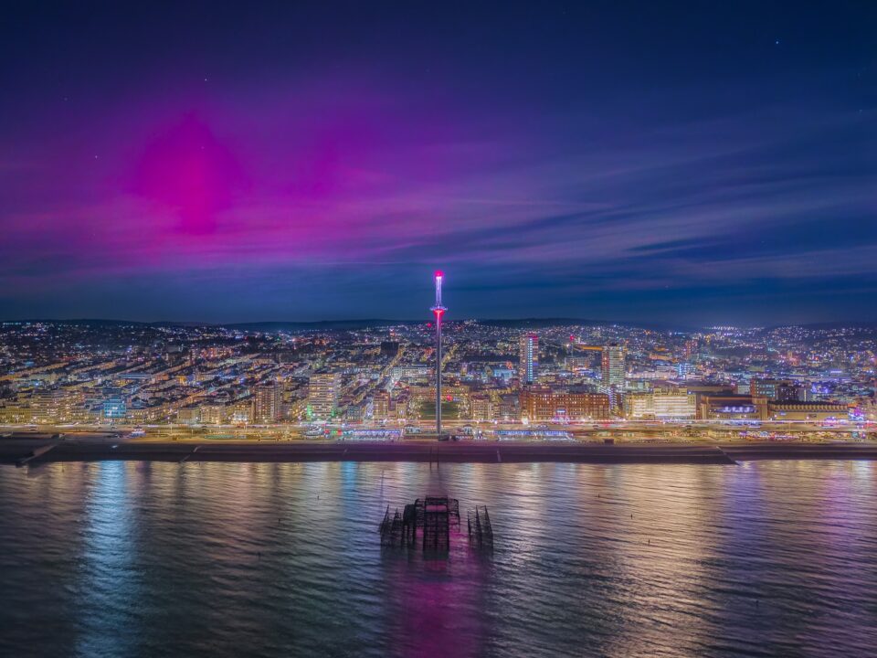 a bright pink light illuminates a blue sky above a nighttime cityscape