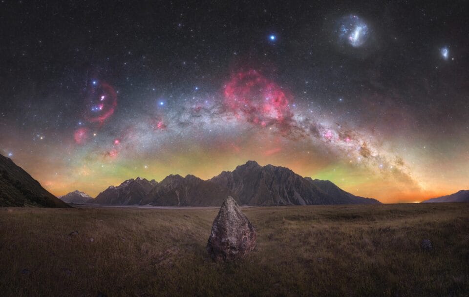 pink and purple bursts appear above a wide-angle shot of mountains