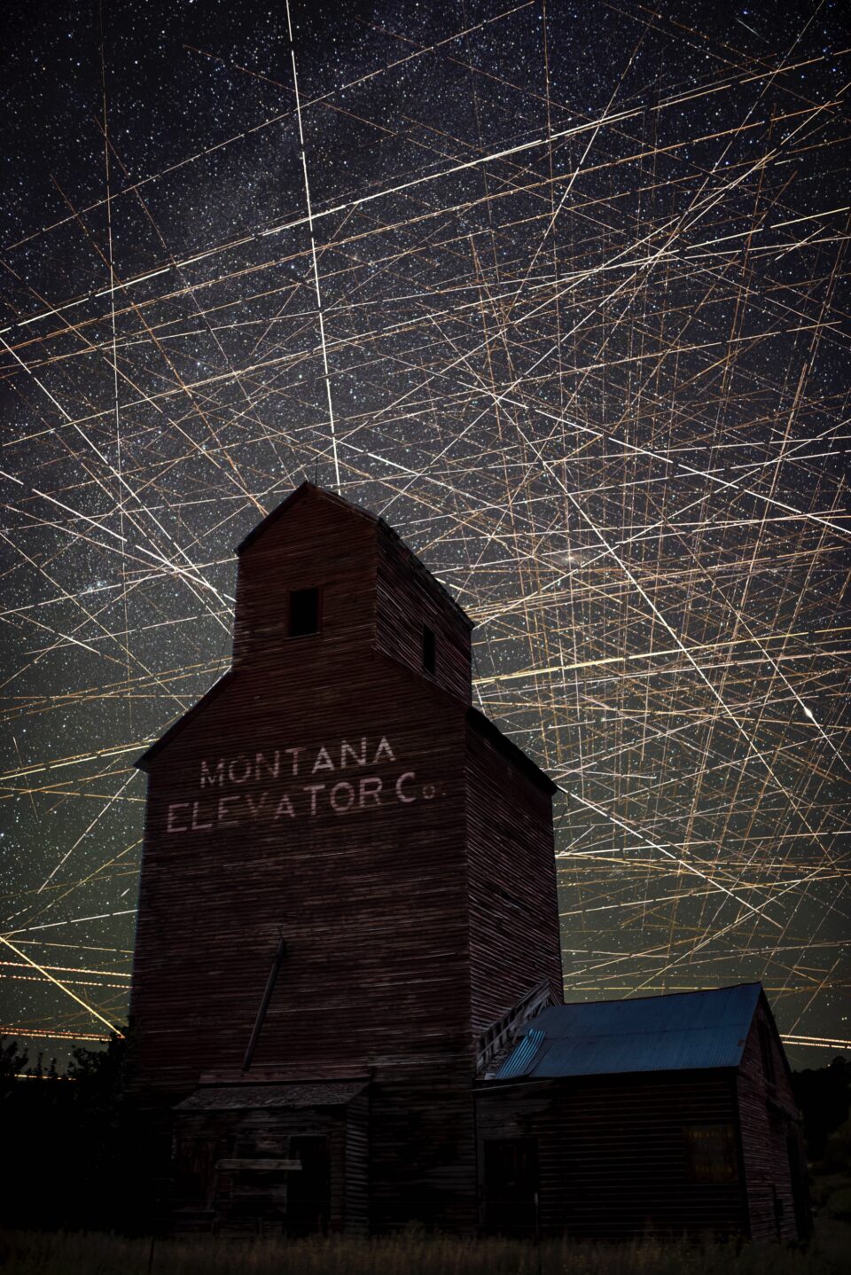 streaks of lights crisscross the night sky over an illuminated montana elevator building