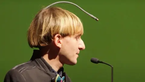 First Born Films Neil Harbisson side view of him and his antennae, which starts at the back of his head and goes in an arc to above his forehead