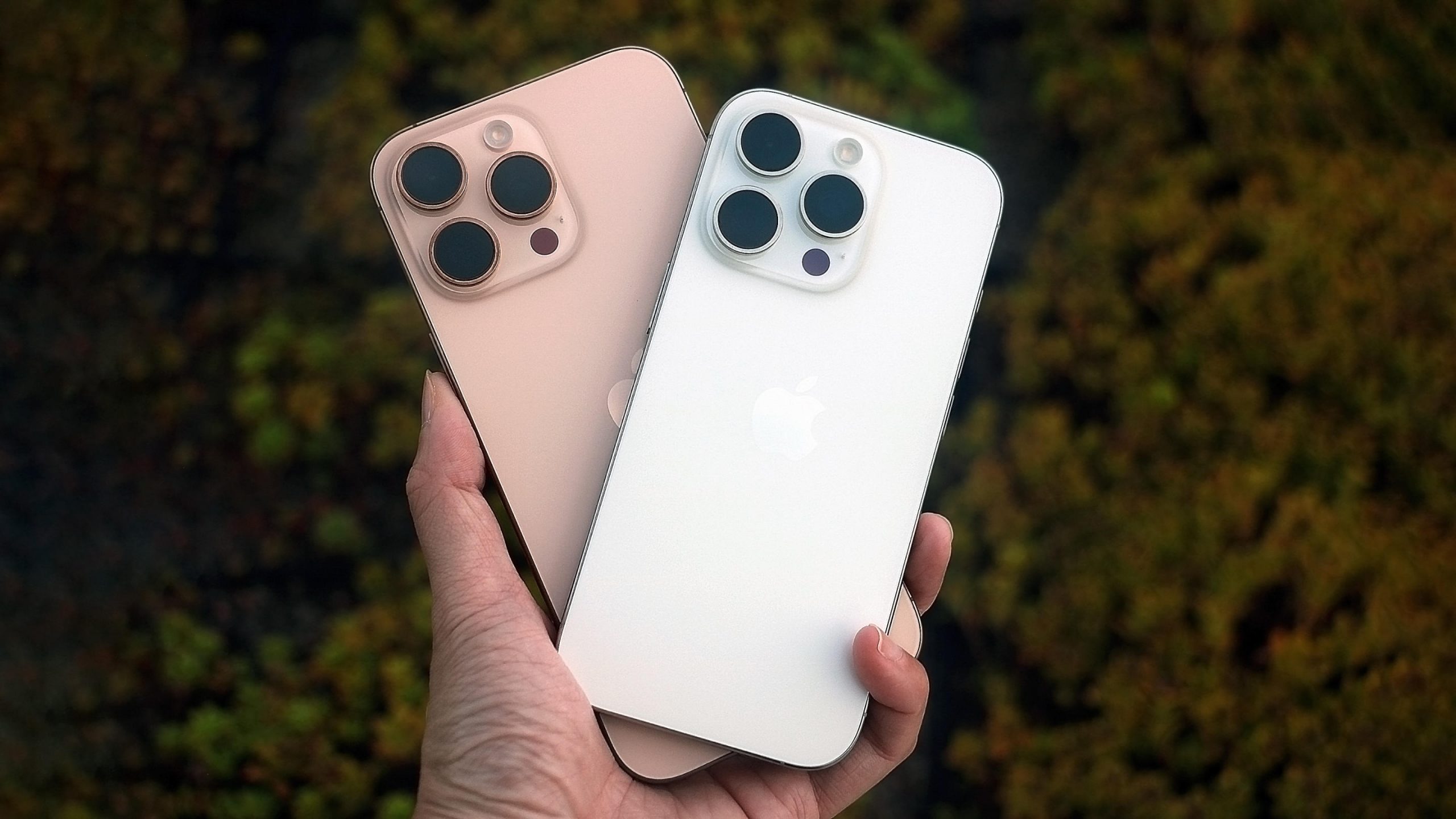 The iPhone 16 Pro and iPhone 16 Pro Max held in mid air with their backs facing up.