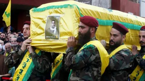 Reuters Hezbollah members carry the coffin, draped in yellow, of Hassan Youssef Abdel Sater who was killed on Friday in an Israeli strike on Beirut's southern suburbs