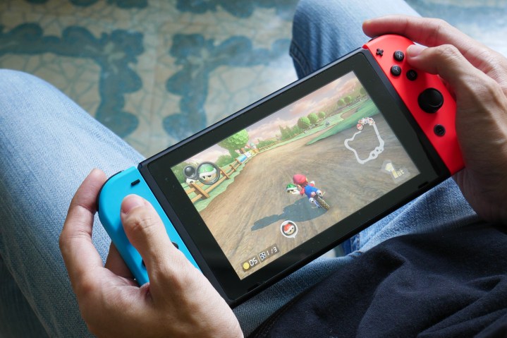 A person plays Mario Kart 8 Deluxe on a Nintendo Switch in handheld mode.