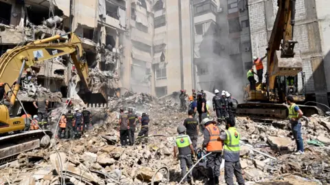 EPA Emergency workers use excavators to clear the rubble at the site which was targeted by an Israeli strike the previous day, in the southern suburb of Beirut, Lebanon