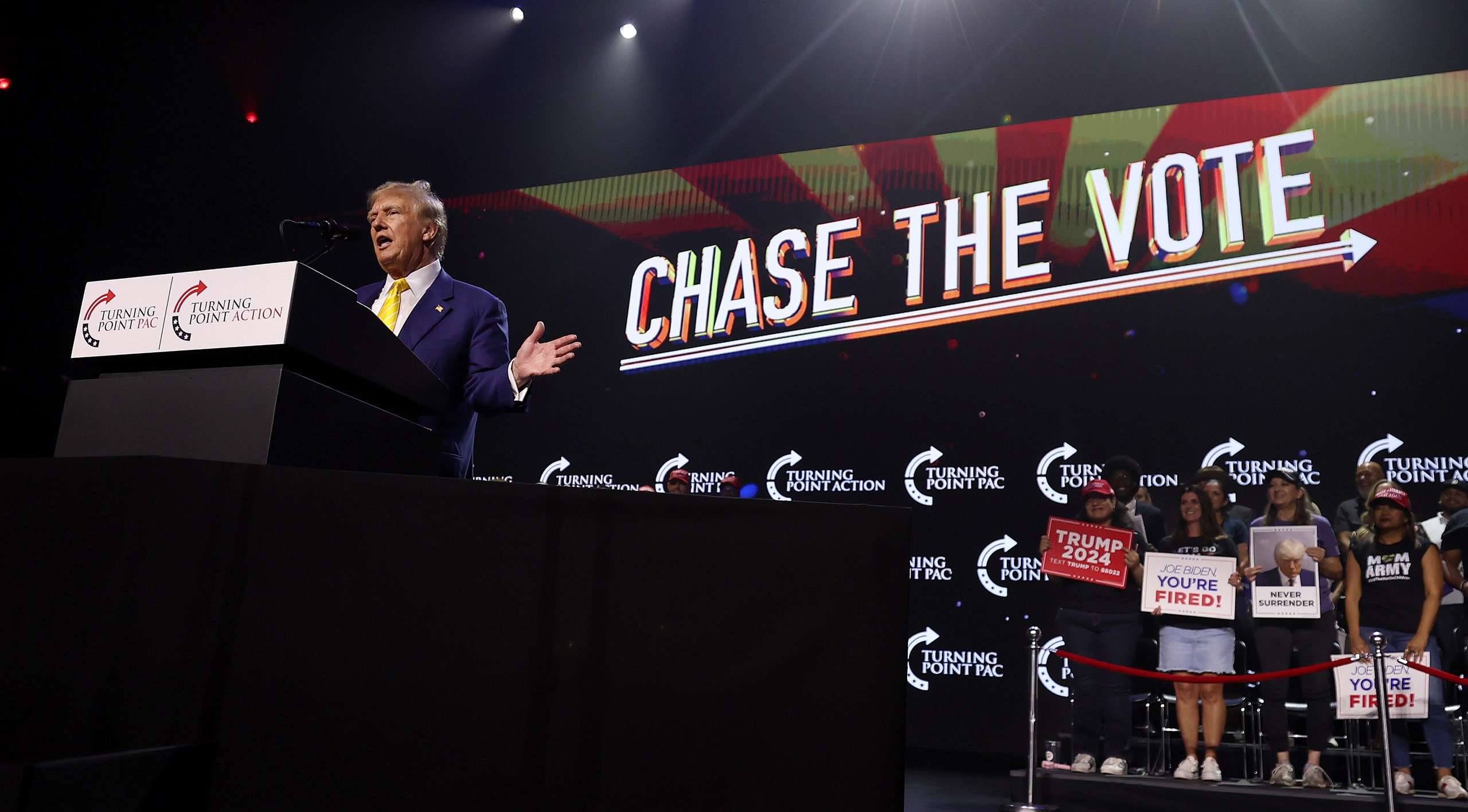 Donald Trump speaking in front of a sign that says CHASE THE VOTE.