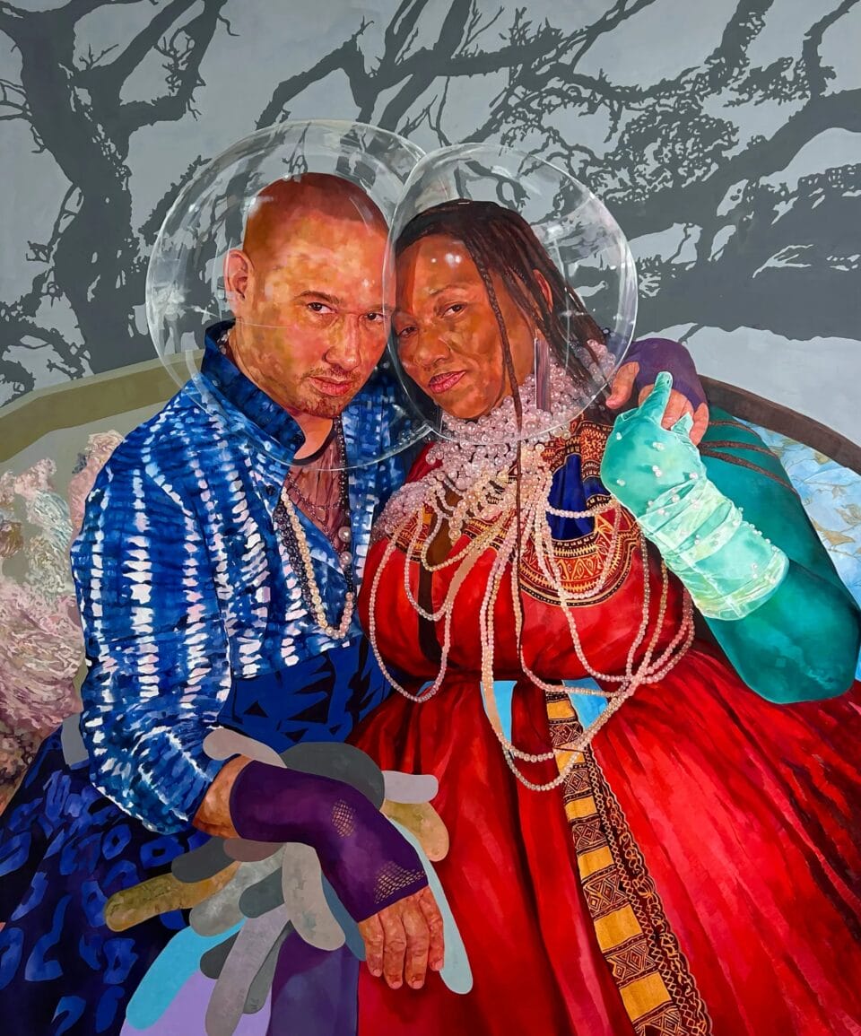 two people in clear bubbles embrace while wearing elaborate gowns and beads