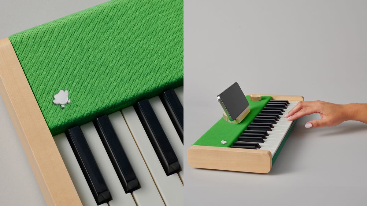 A small piano with green felt and a smartphone on it