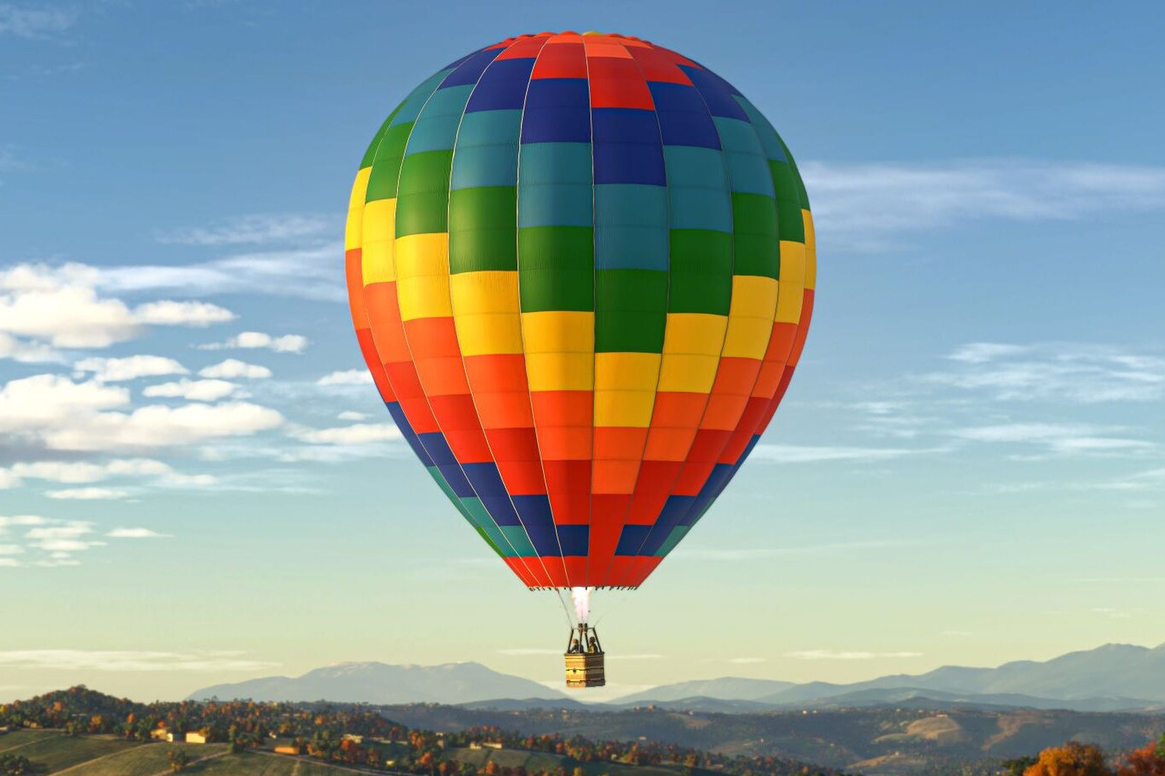 A rainbow colored hot air balloon in flight in Microsoft Flight Simulator 2024.