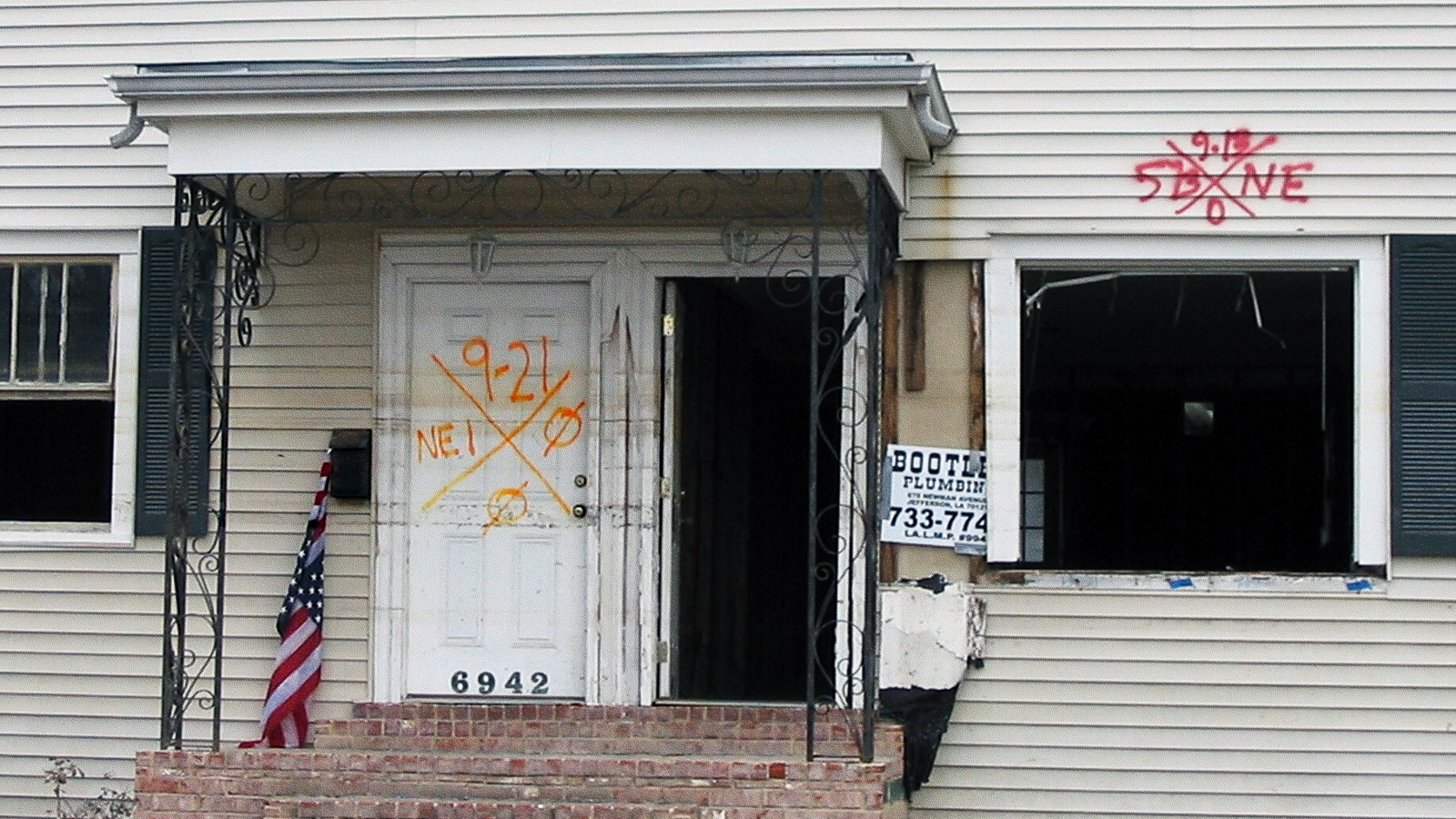 A closeup of the front of an abandoned house that is boarded up