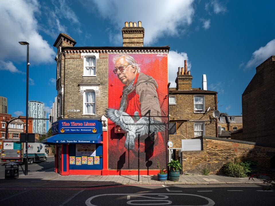 a mural of an older white man with a pigeon flying in front of him