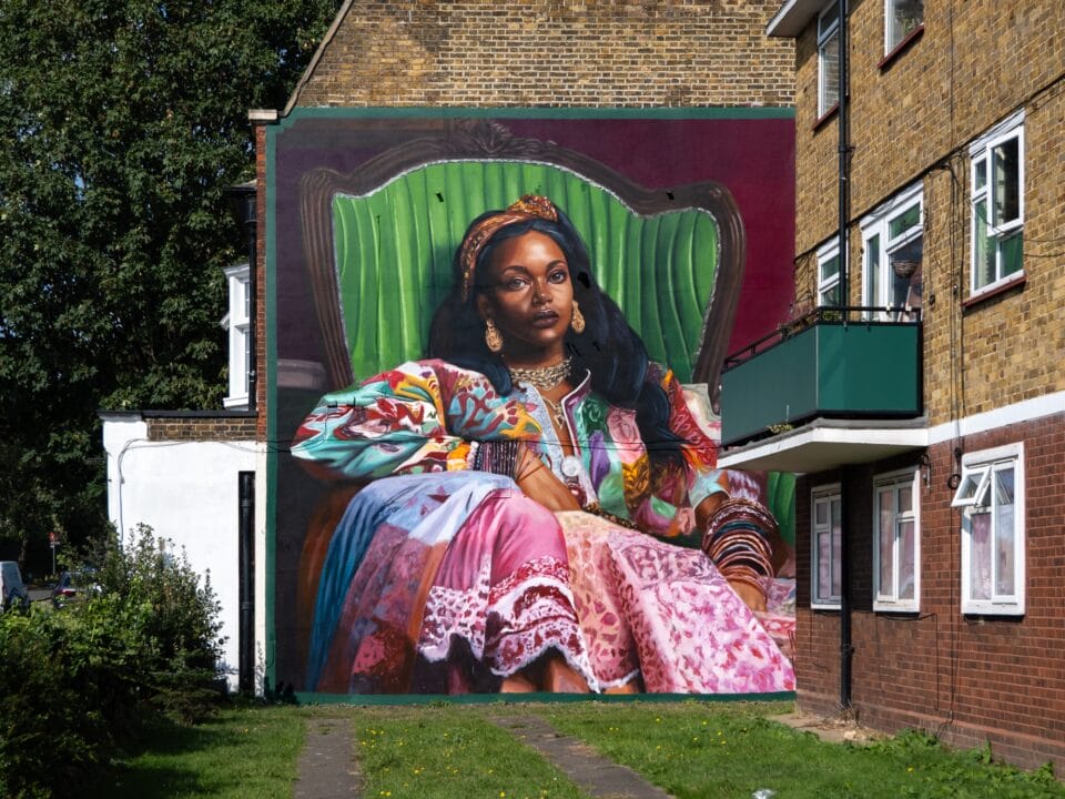 a mural of a regal Black woman in a green chair and lavish patterned gown