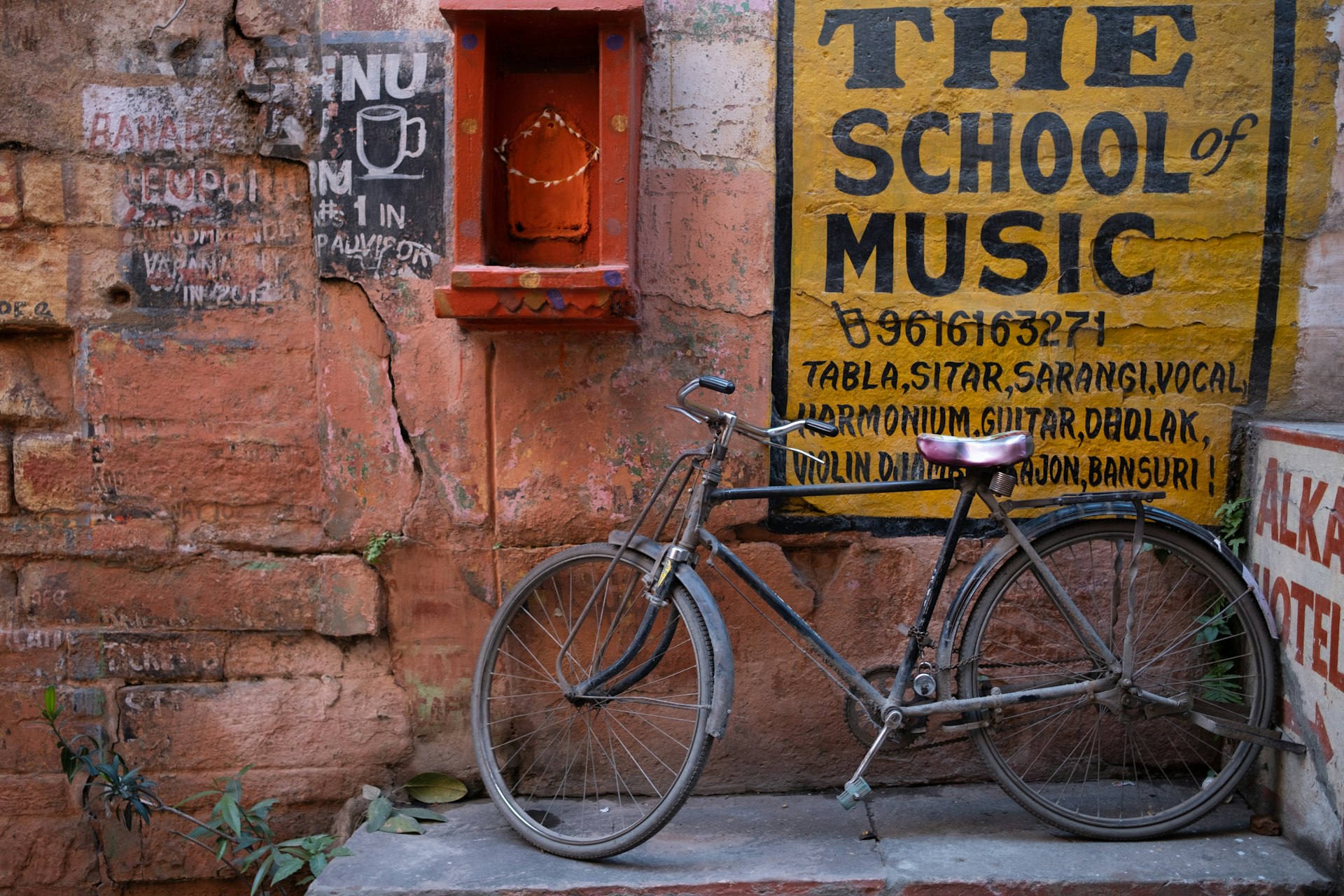 A bicycle in an alley parked next to hand-painted signs in an alley of Old Town Varanasi, India