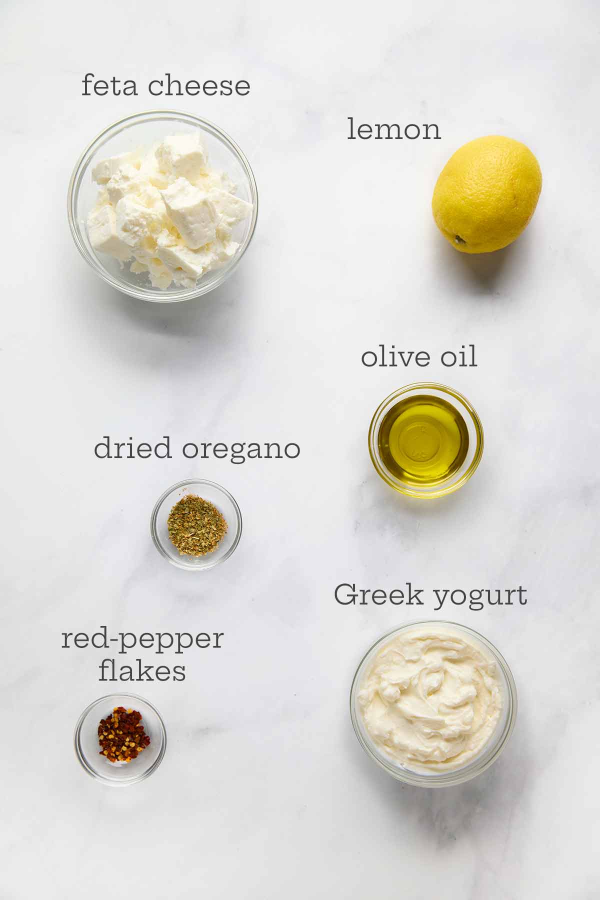 Ingredients for whipped feta dip--feta cheese, lemon, olive oil, oregano, yogurt, and pepper flakes.