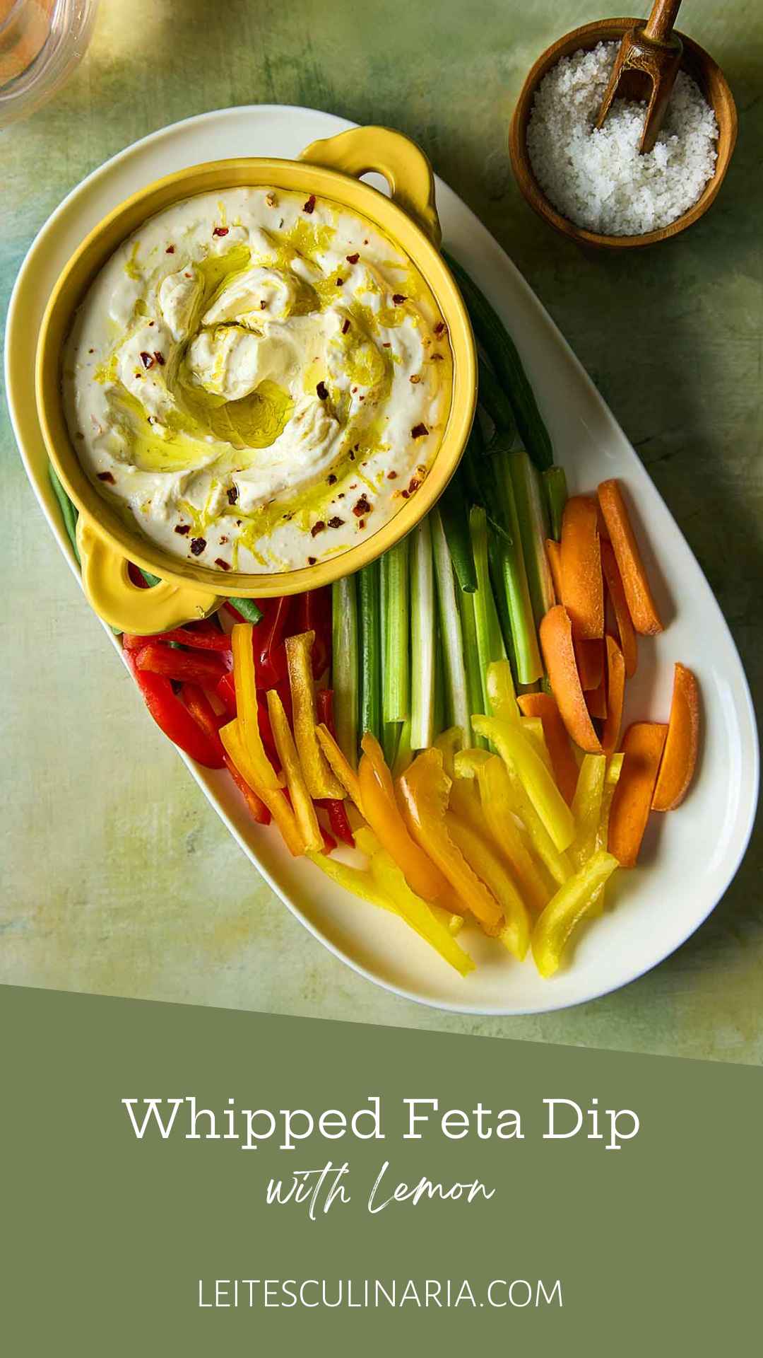 A bowl of whipped feta dip topped with oil and lemon zest on a platter of raw vegetables.